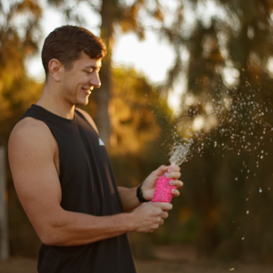 A photo of a runner spraying a soft flask. To demonstrate the easy flow valve.